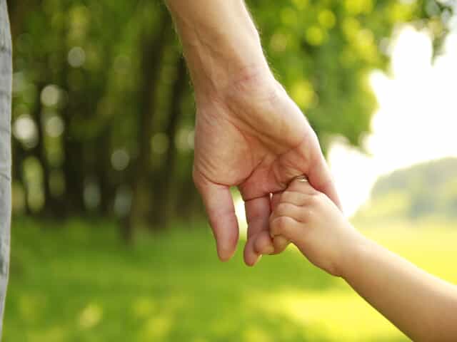 Establishing Paternity - Father holding child's hand outside